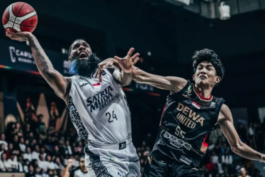 Pemain Dewa United Banten Radithyo Wibowo (kanan) menghadang pebasket Satria Muda Pertamina Jakarta, Reynaldo Garcia, yang melakukan lay up dalam pertandingan babak reguler IBL 2024 di Dewa United Arena, Banten, Sabtu (6/7/2024).